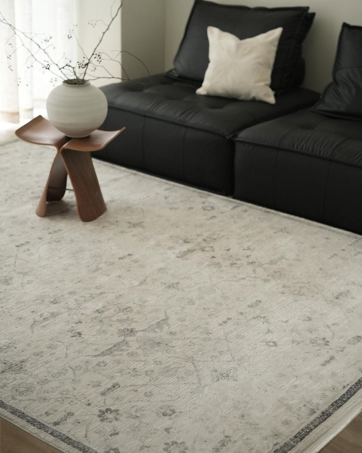 Light grey patterned rug in a living room next to a black sofa