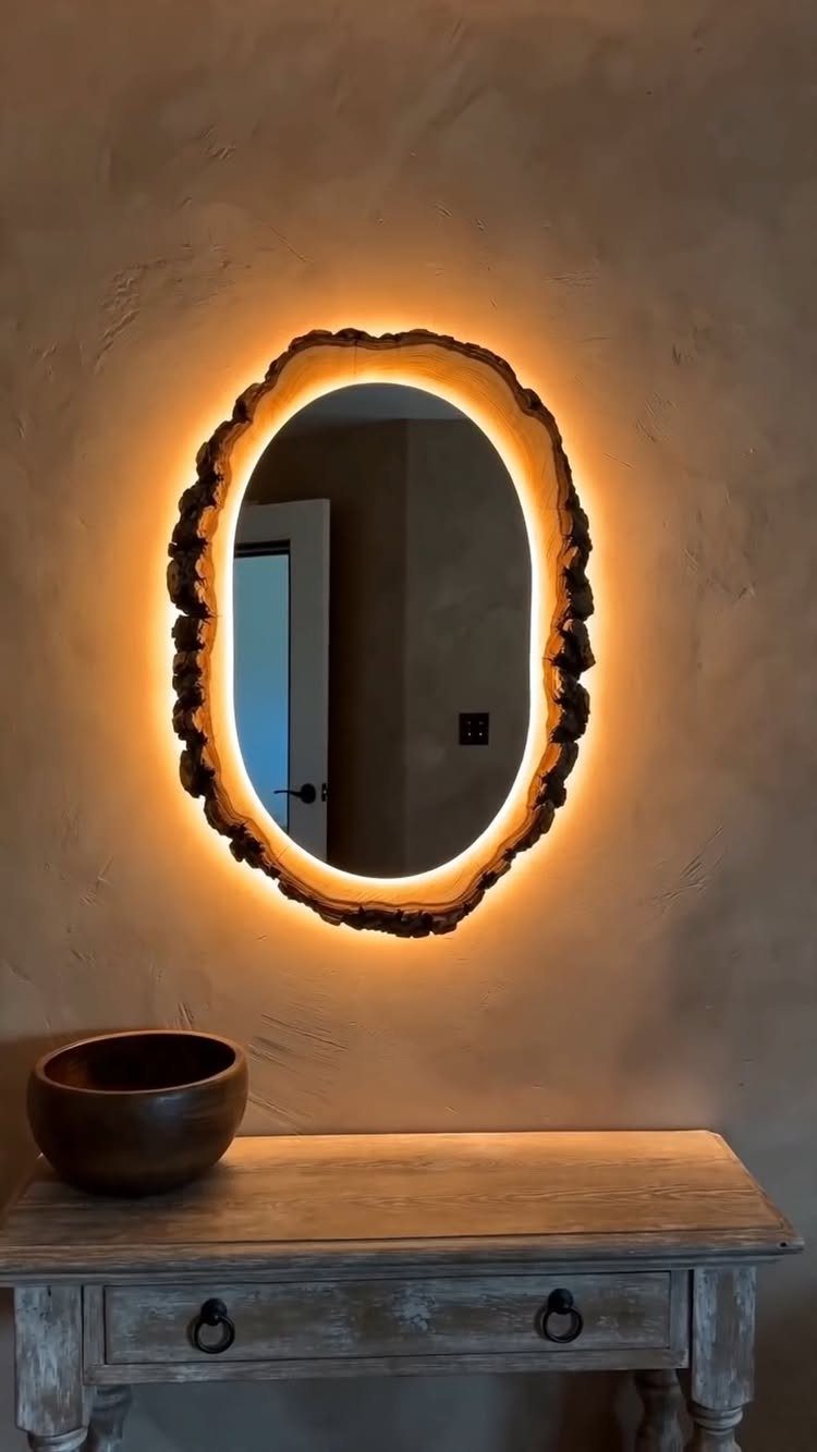 Backlit organic wooden mirror hanging above a rustic weathered wooden console table.