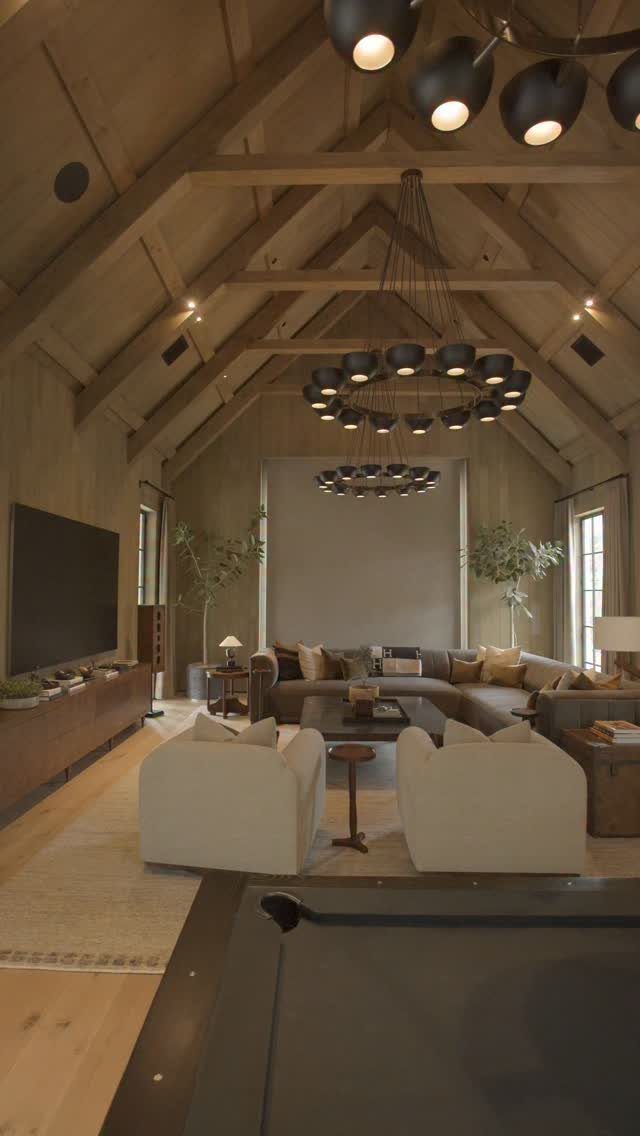 Rustic contemporary living room with vaulted wooden ceilings and modern circular chandeliers.