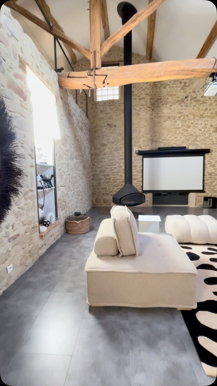 Living room with large natural wood exposed beams and stone walls.