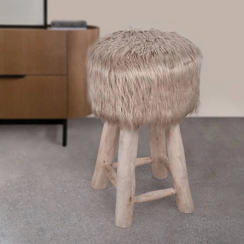 Furry beige stool with natural log legs on a grey concrete floor
