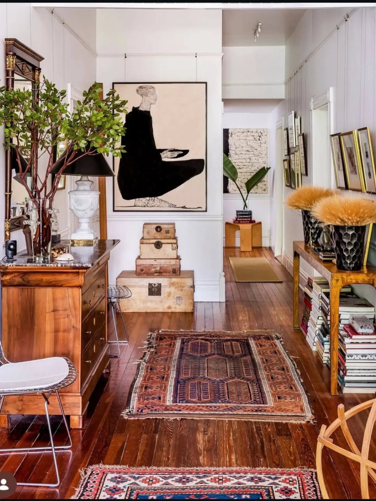 Eclectic living room with hardwood floors, patterned rugs, and large wall art.