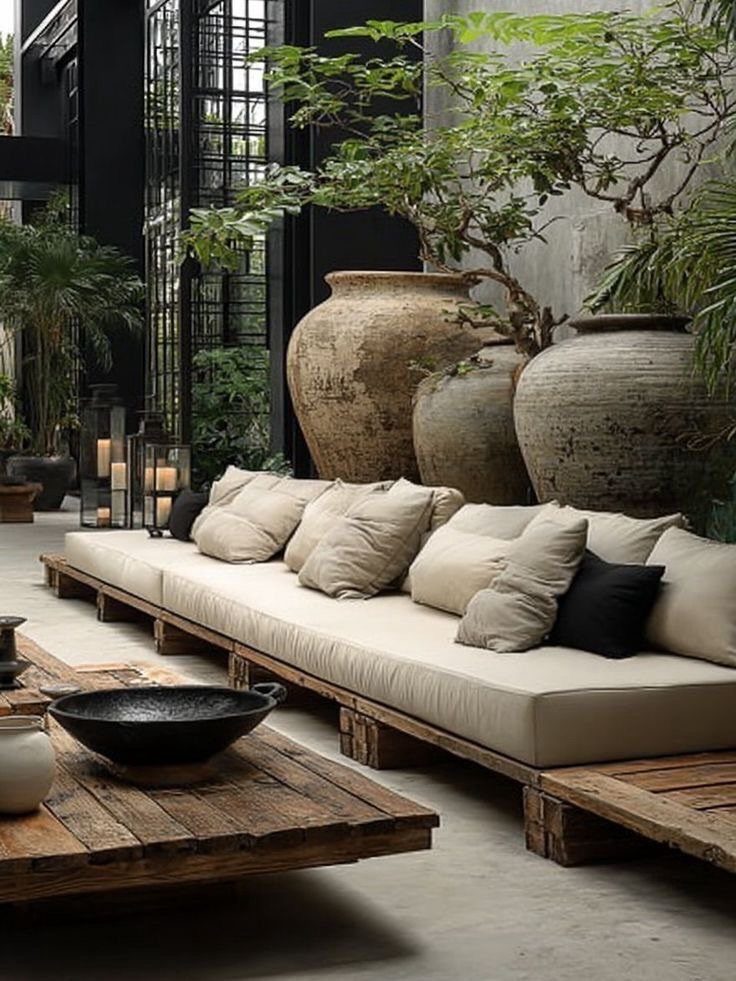 Low cream sofa on wooden pallets with rustic coffee table and large clay pots.