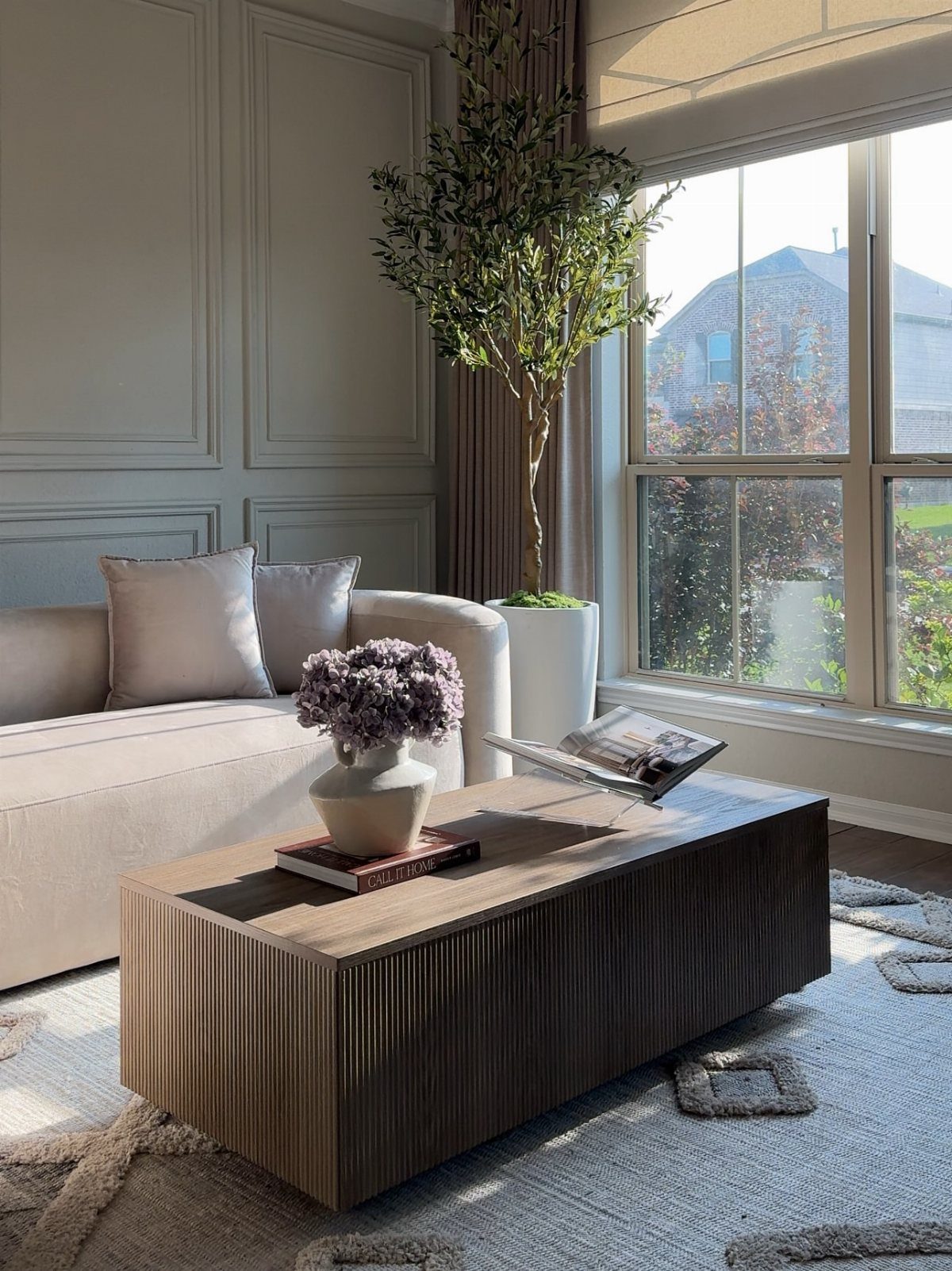 Light fabric sectional sofa with a fluted wooden coffee table in a bright room.