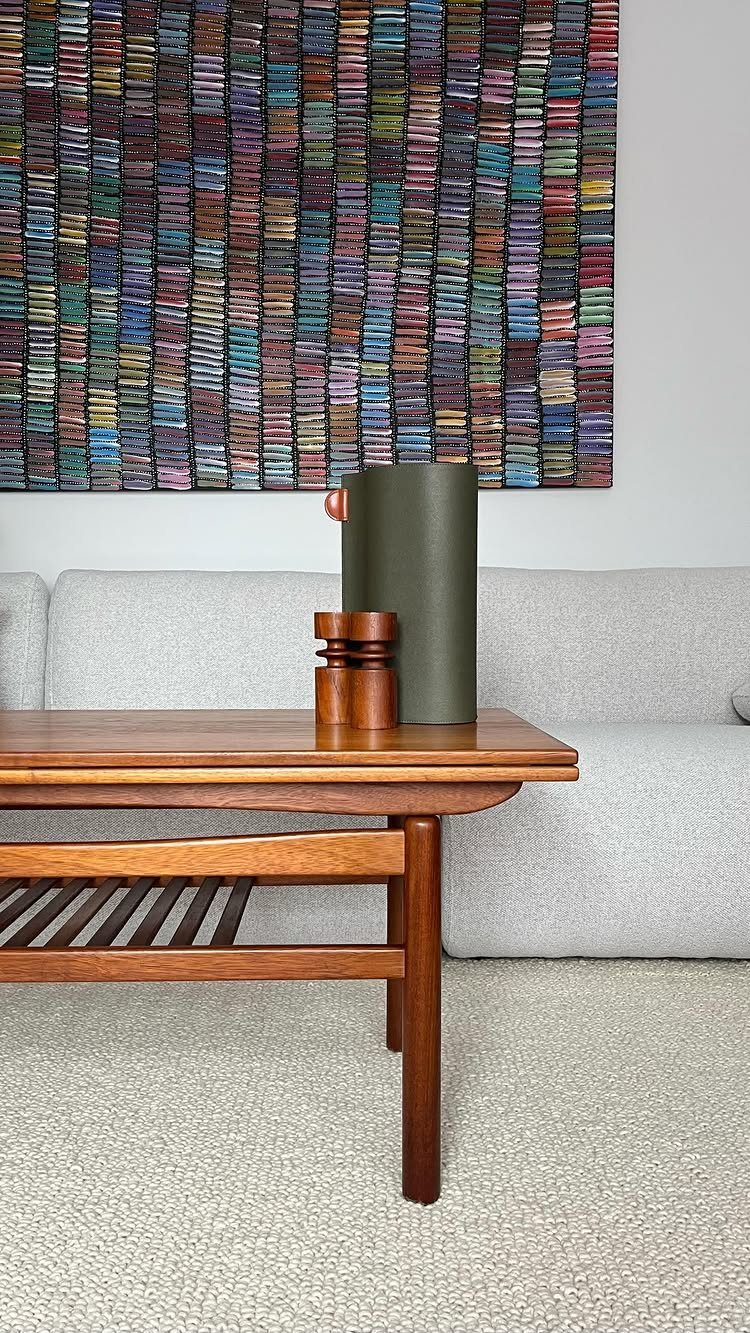 Wooden mid-century modern coffee table with a green vase in a living room.