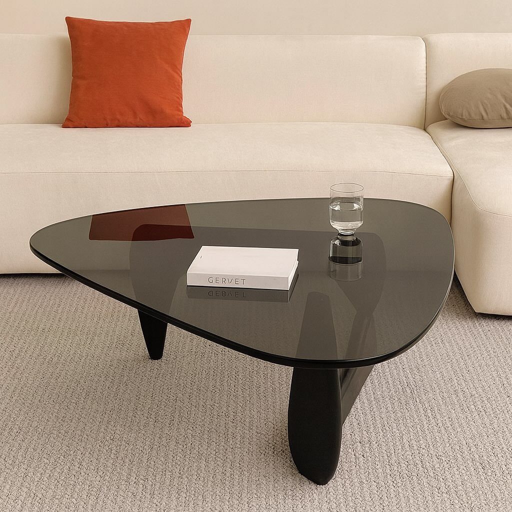 White sectional sofa with a dark triangular glass coffee table on grey carpet.