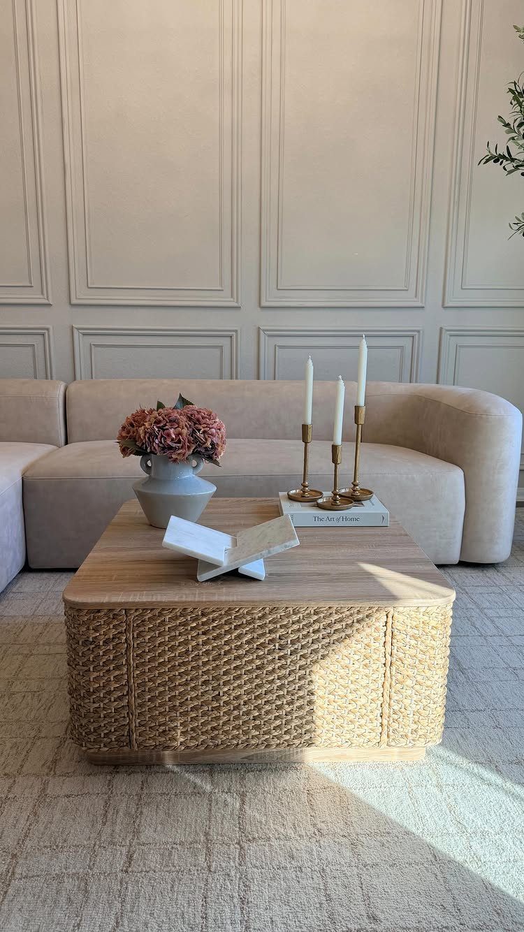 Beige curved sectional sofa with a square woven rattan coffee table in a living room