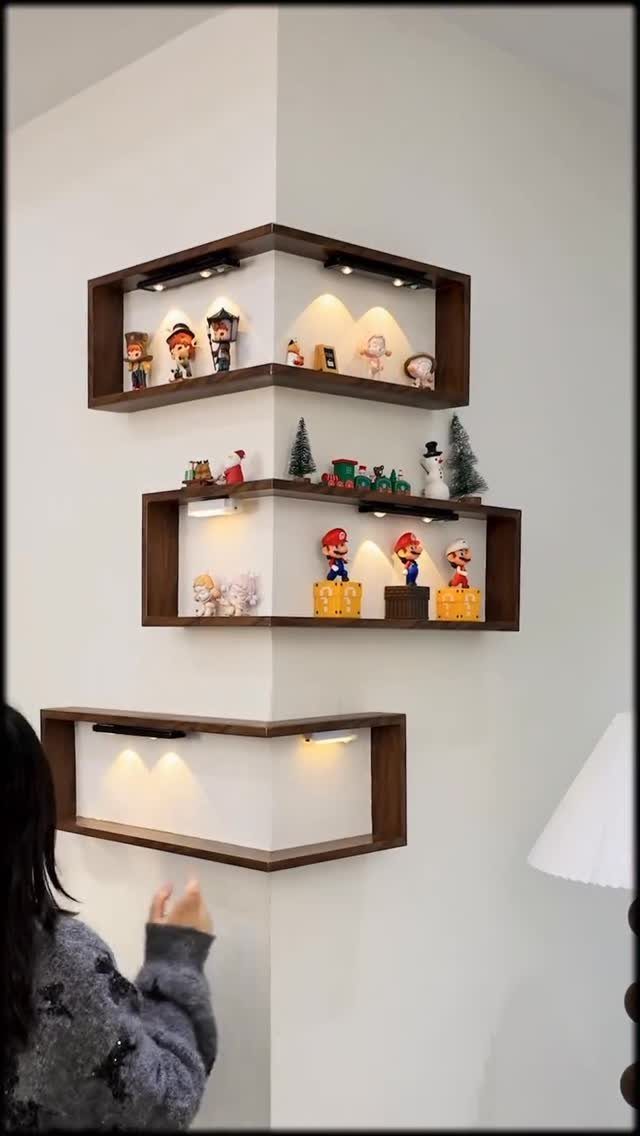 Brown wooden corner shelves with LED lighting displaying small figurines on white walls