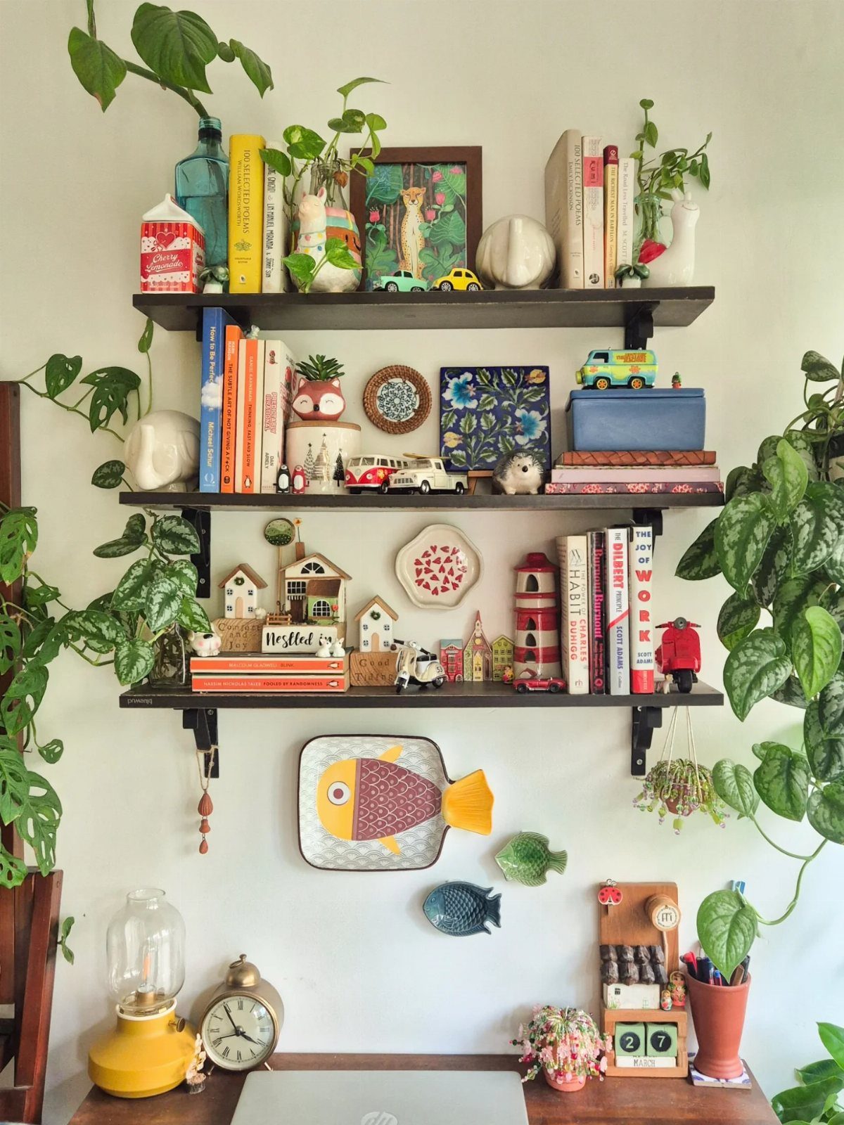 Black wall shelves decorated with colorful books, small plants, and ceramic figurines.