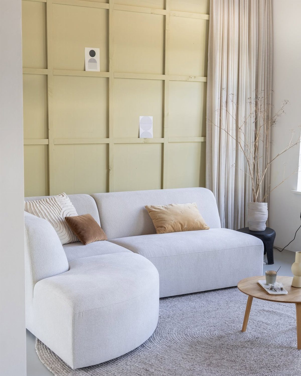 Curved light grey sectional sofa with neutral pillows in a bright living room