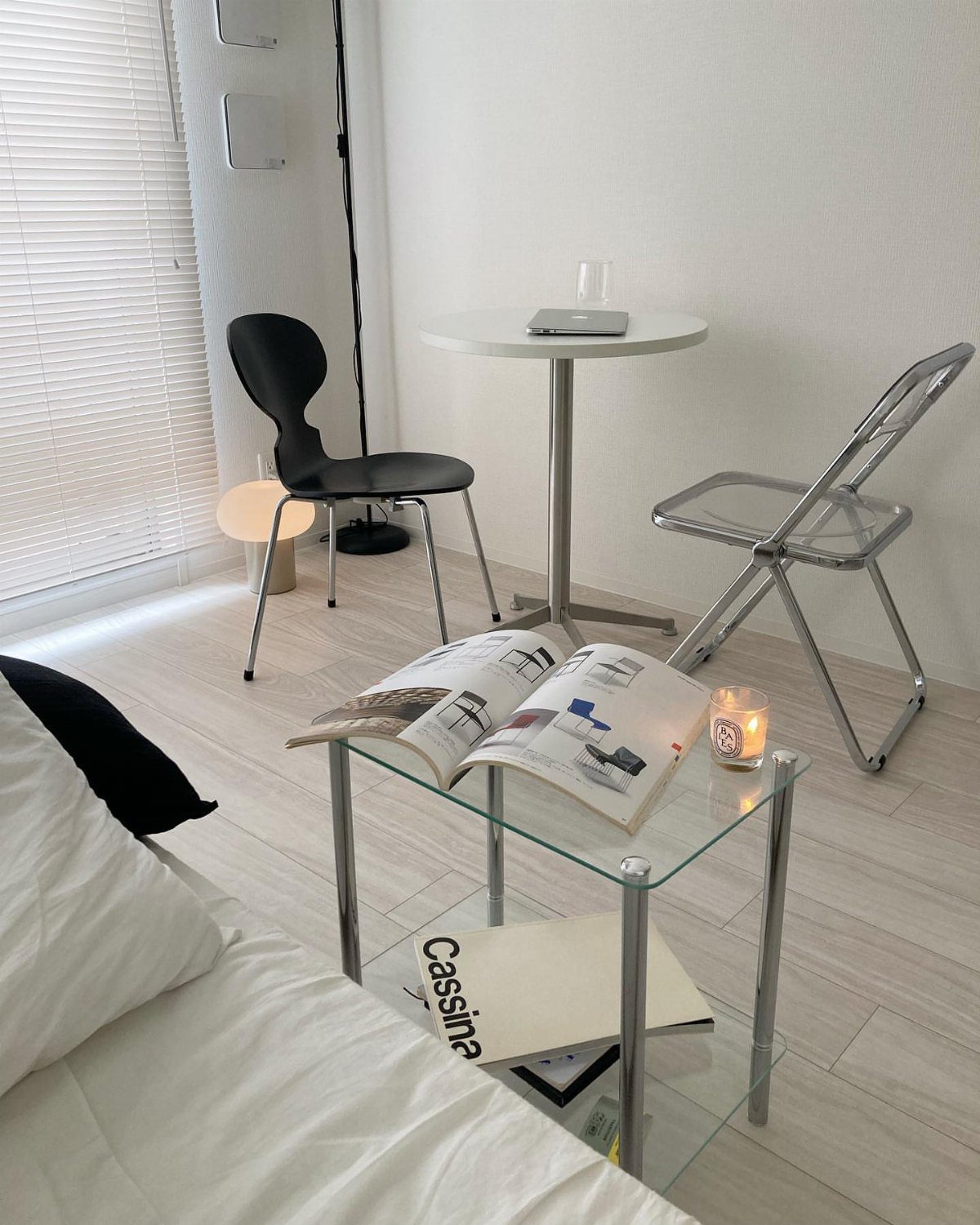 Glass coffee table with a magazine and candle in a bright minimalist room