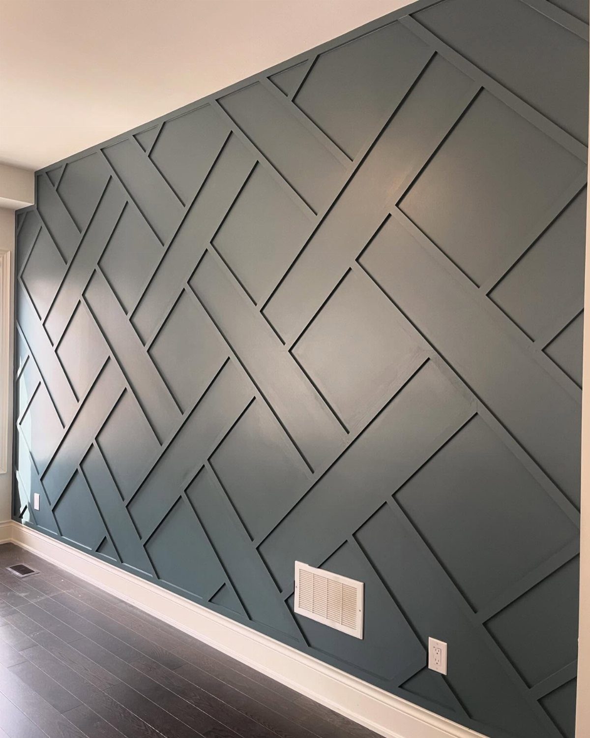 Teal accent wall with a geometric raised wood slat pattern and dark floors.
