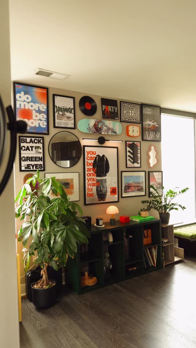 Gallery wall with eclectic art and a skateboard above a green storage shelf.