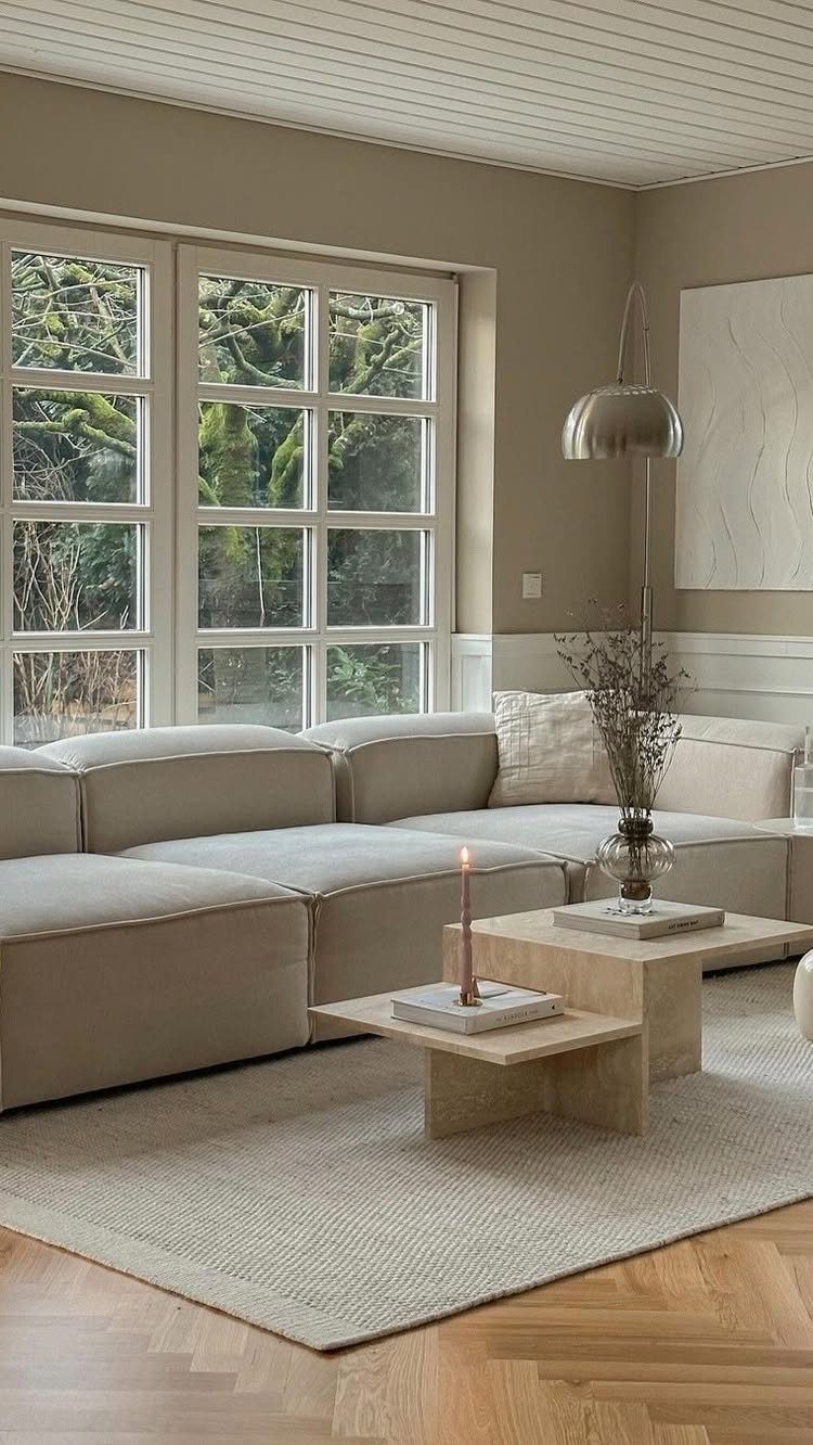 Beige modular sectional sofa with travertine coffee tables in a neutral living room