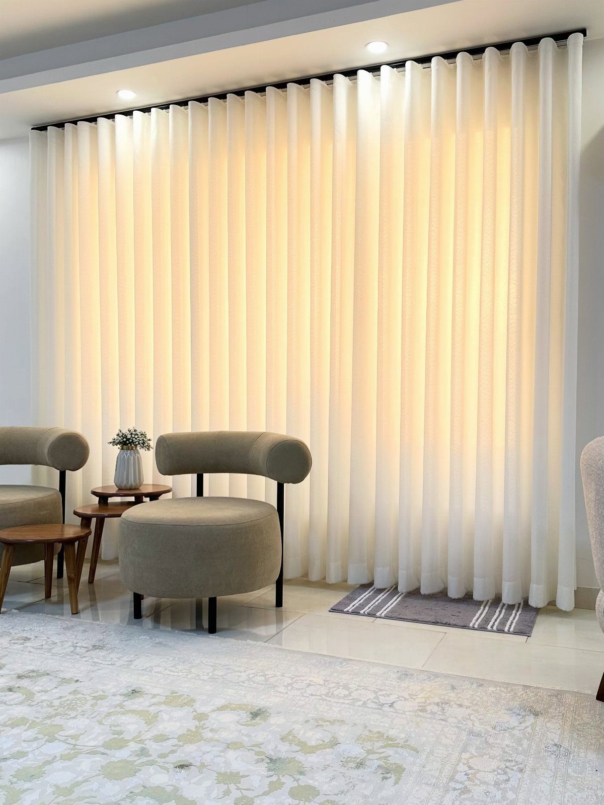 White sheer curtains covering a window in a room with beige armchairs.