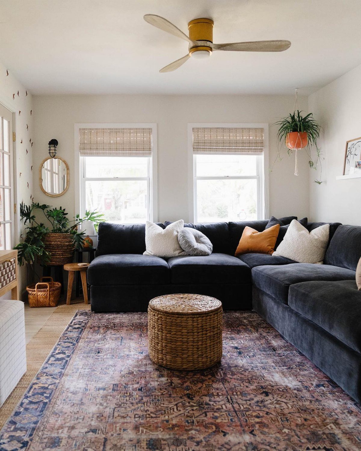 Large navy blue sectional sofa in a small living room with a woven table.