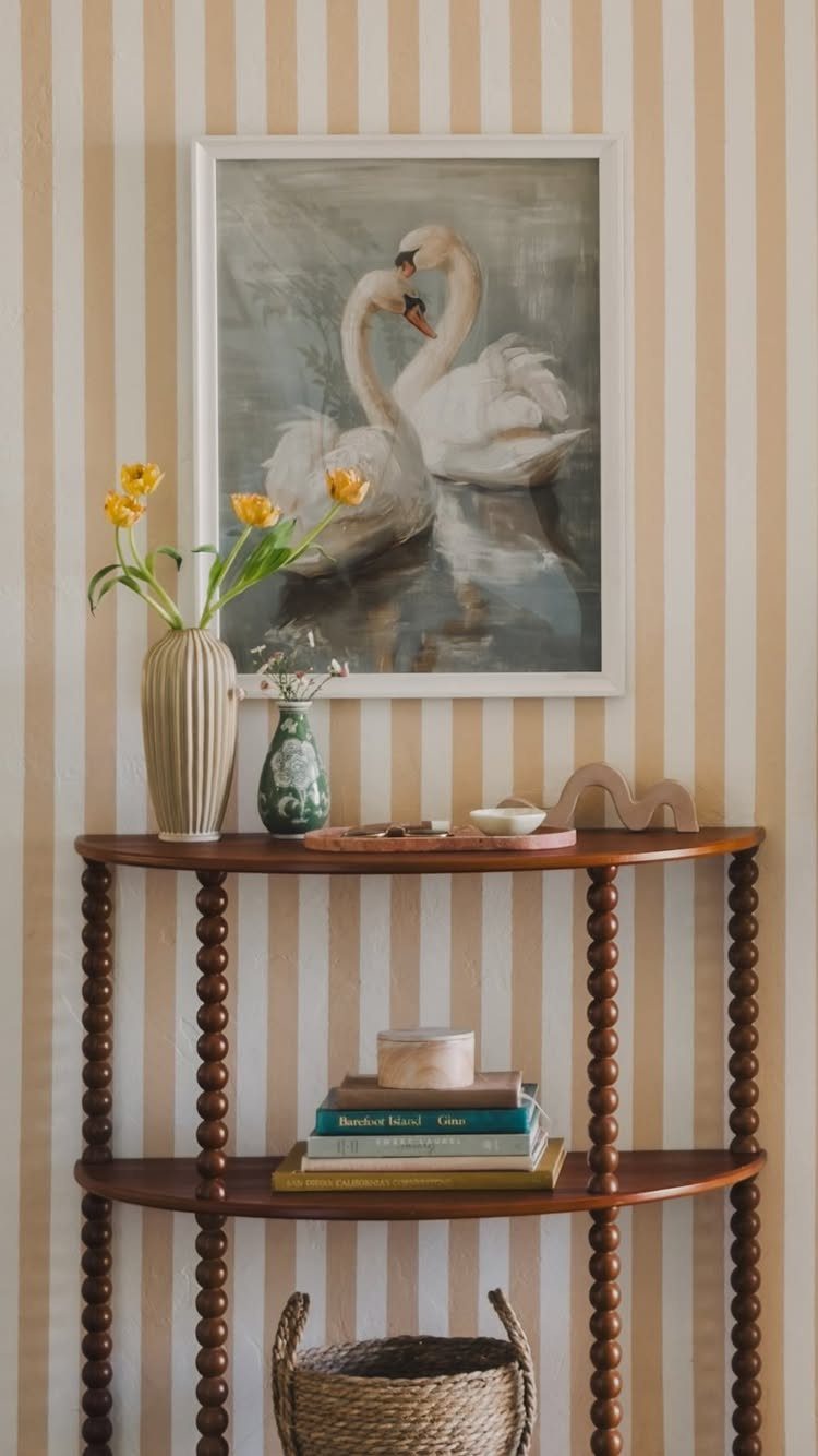 Wooden bobbin shelf with yellow tulips and swan painting against striped wallpaper