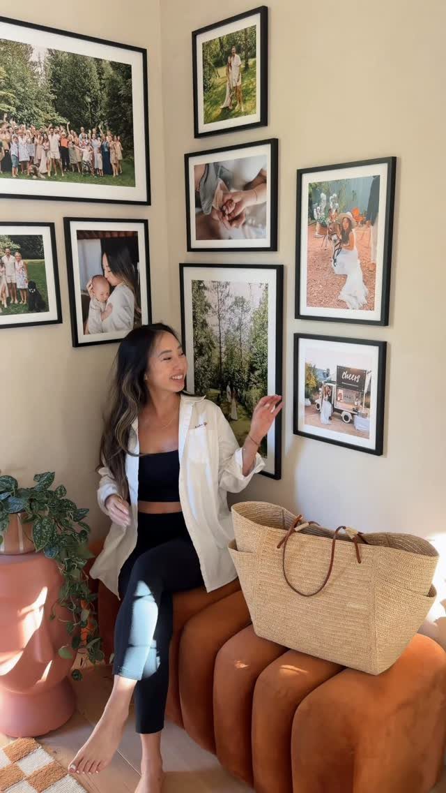 Woman sitting on a brown sofa in front of a gallery wall of photos