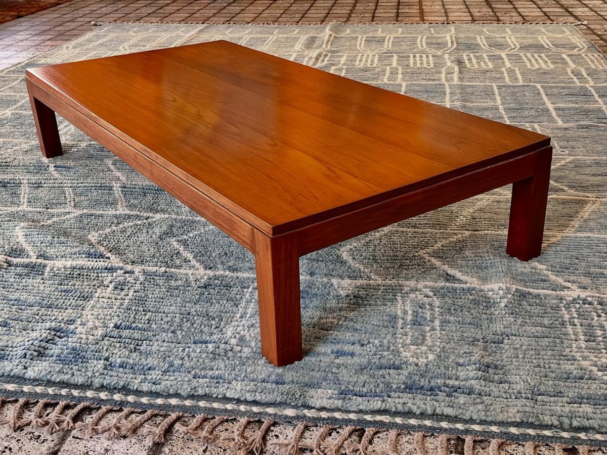 Low rectangular wooden coffee table on a blue patterned rug over brick flooring