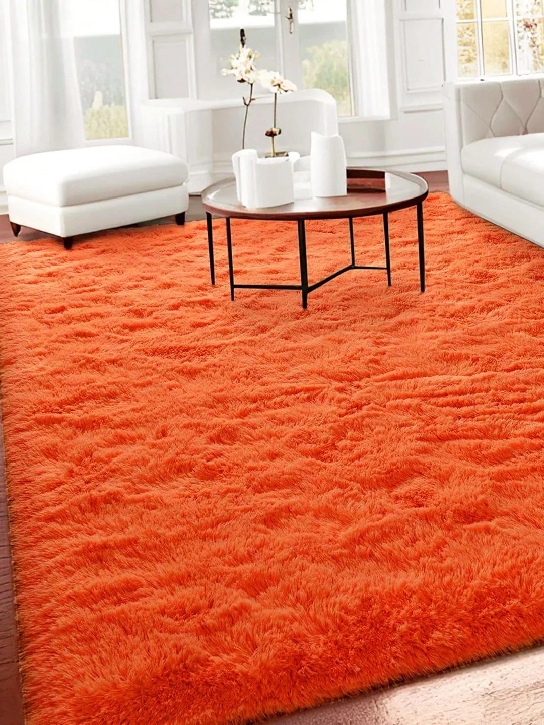 Bright orange shaggy rug in a white living room with modern furniture.