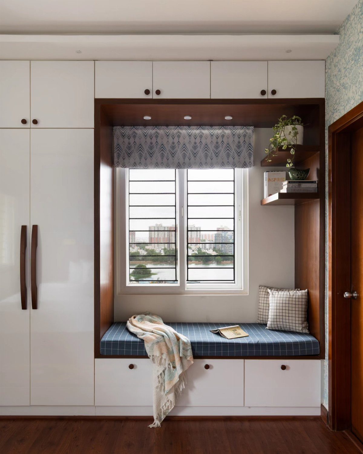 Built-in window seat with blue cushion and white storage drawers beneath a window.