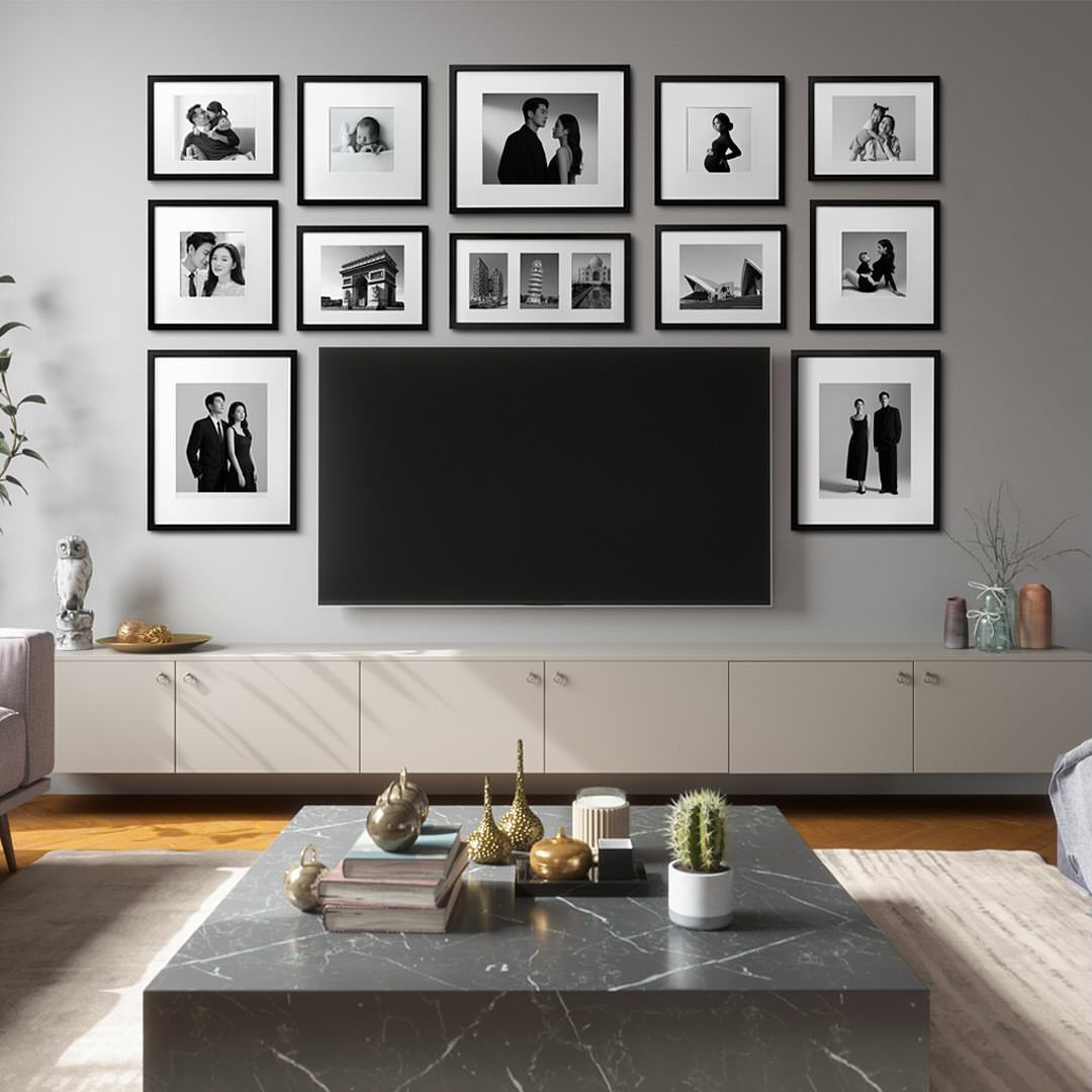 Large black television surrounded by black and white framed photos on a grey wall