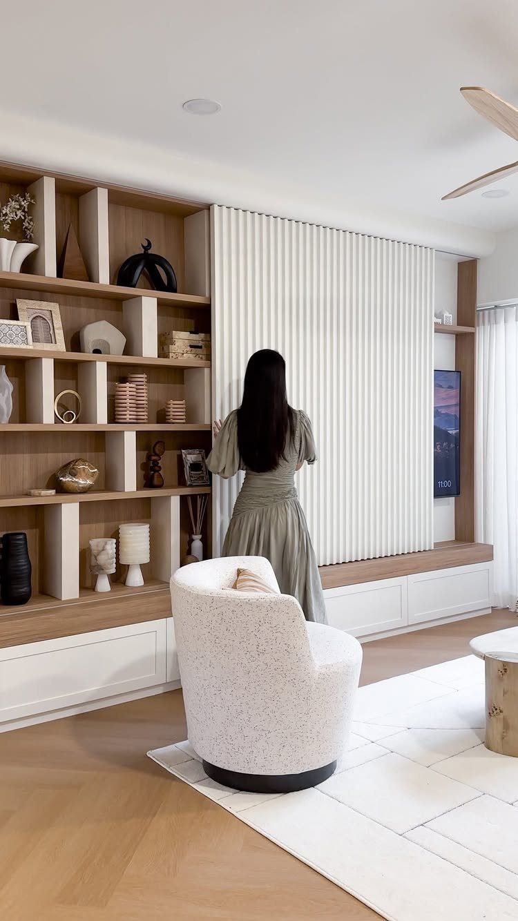 Woman standing by a white slatted sliding panel concealing a TV in a living room.