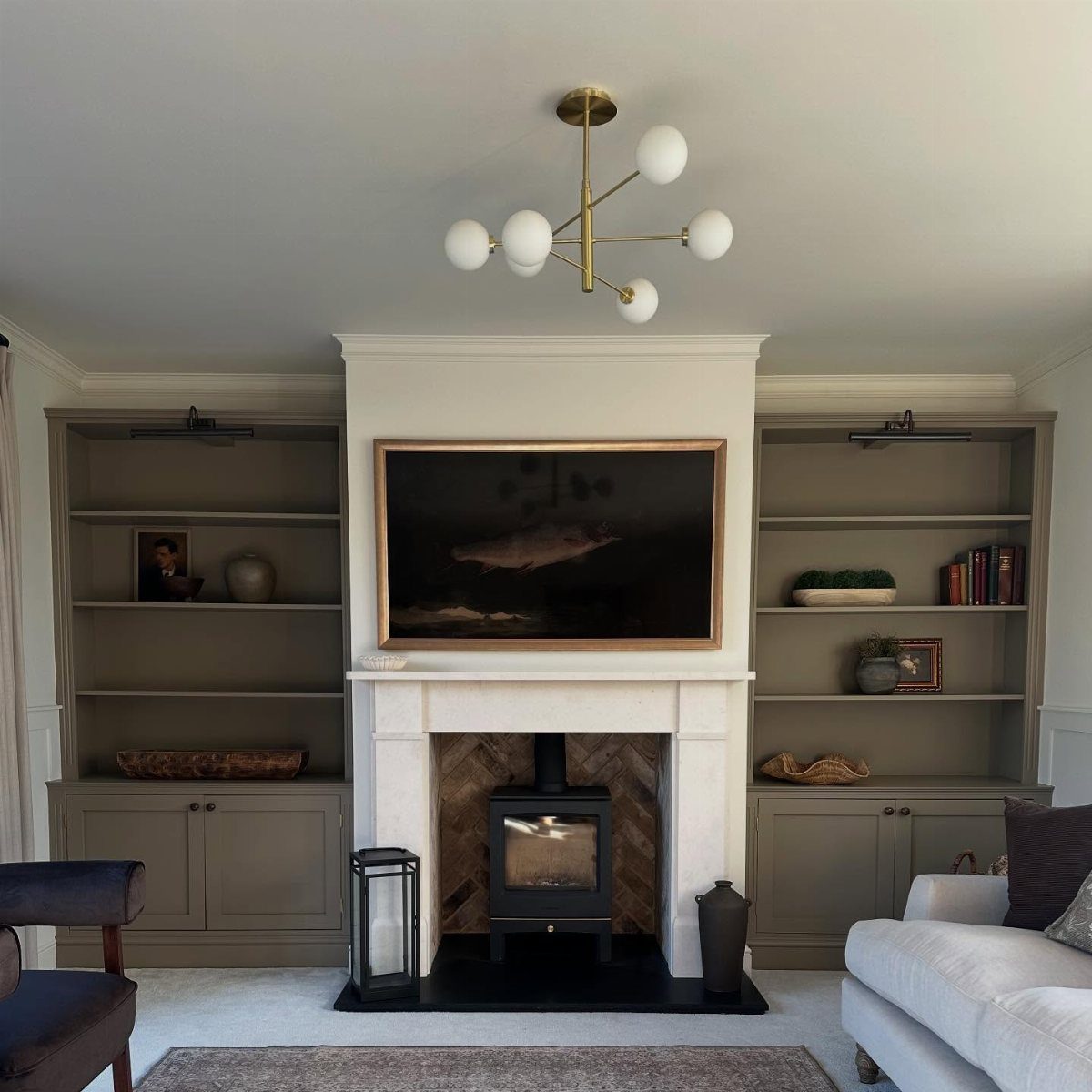 White fireplace with a TV above it and built-in grey shelving units on sides.
