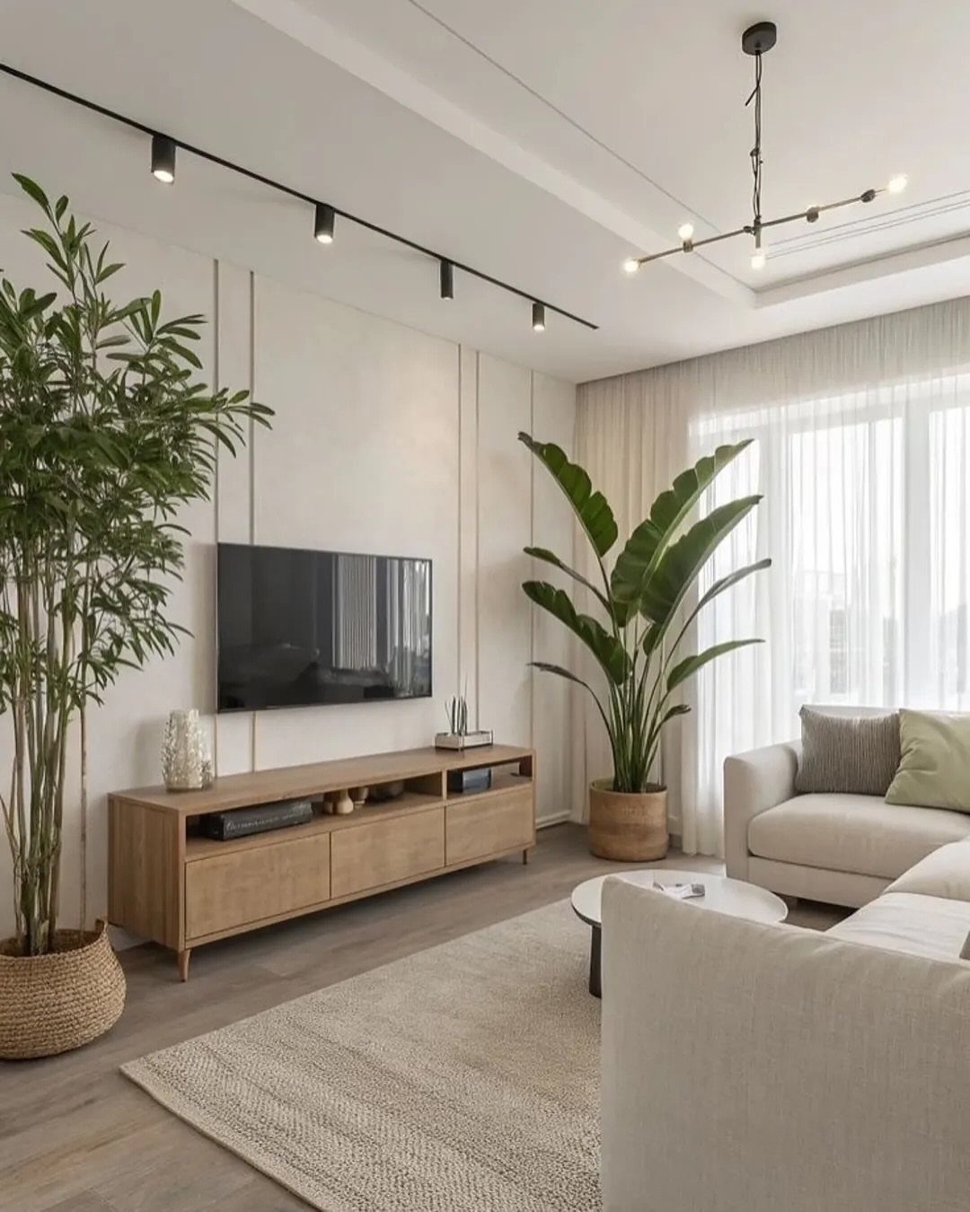 Modern living room with wall-mounted TV, wooden console, beige sofa, and green plants.
