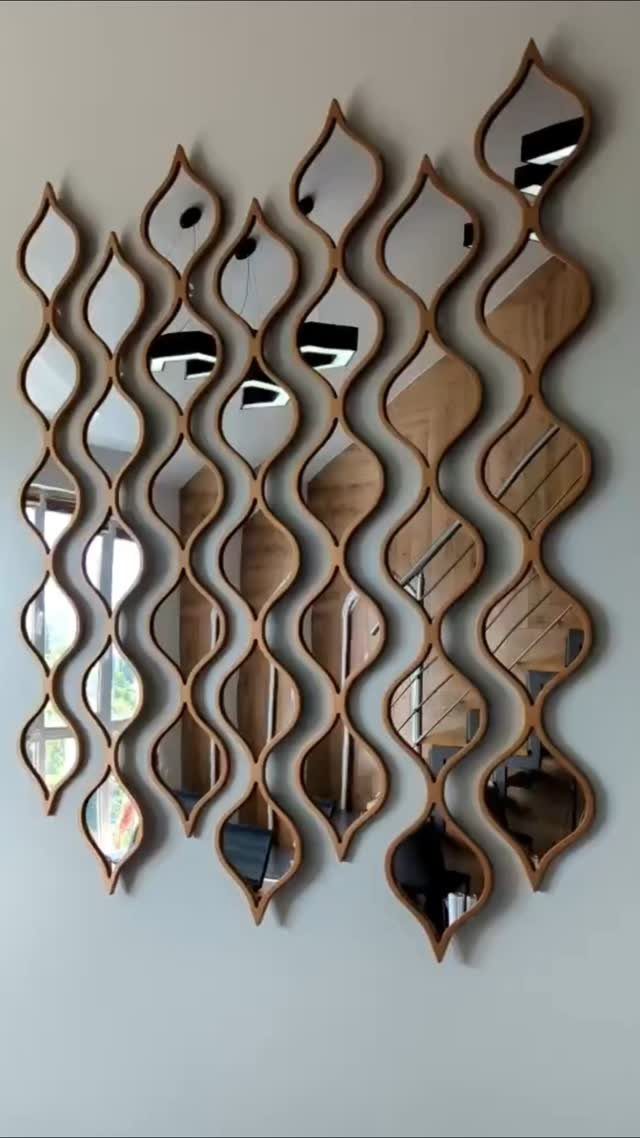 Decorative wavy wooden framed mirrors arranged in vertical columns on a neutral wall.