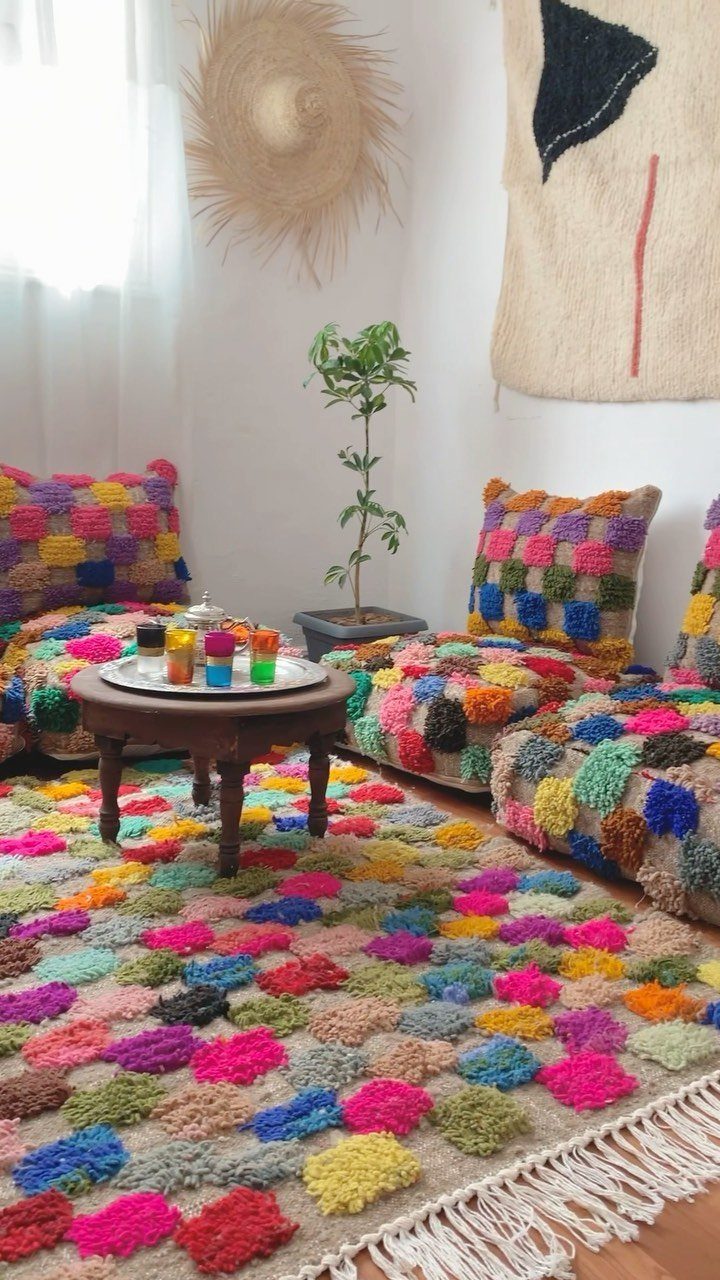 Colorful crocheted poufs and matching rug surrounding a small wooden coffee table.