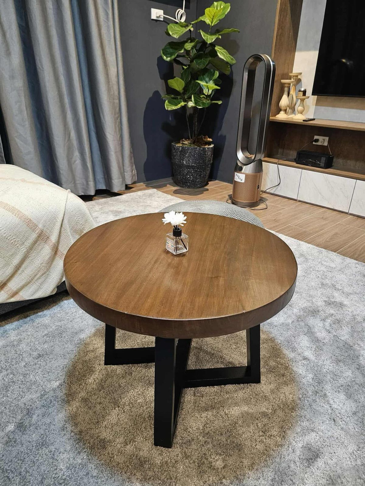 Round wooden coffee table on a grey rug in a modern living room