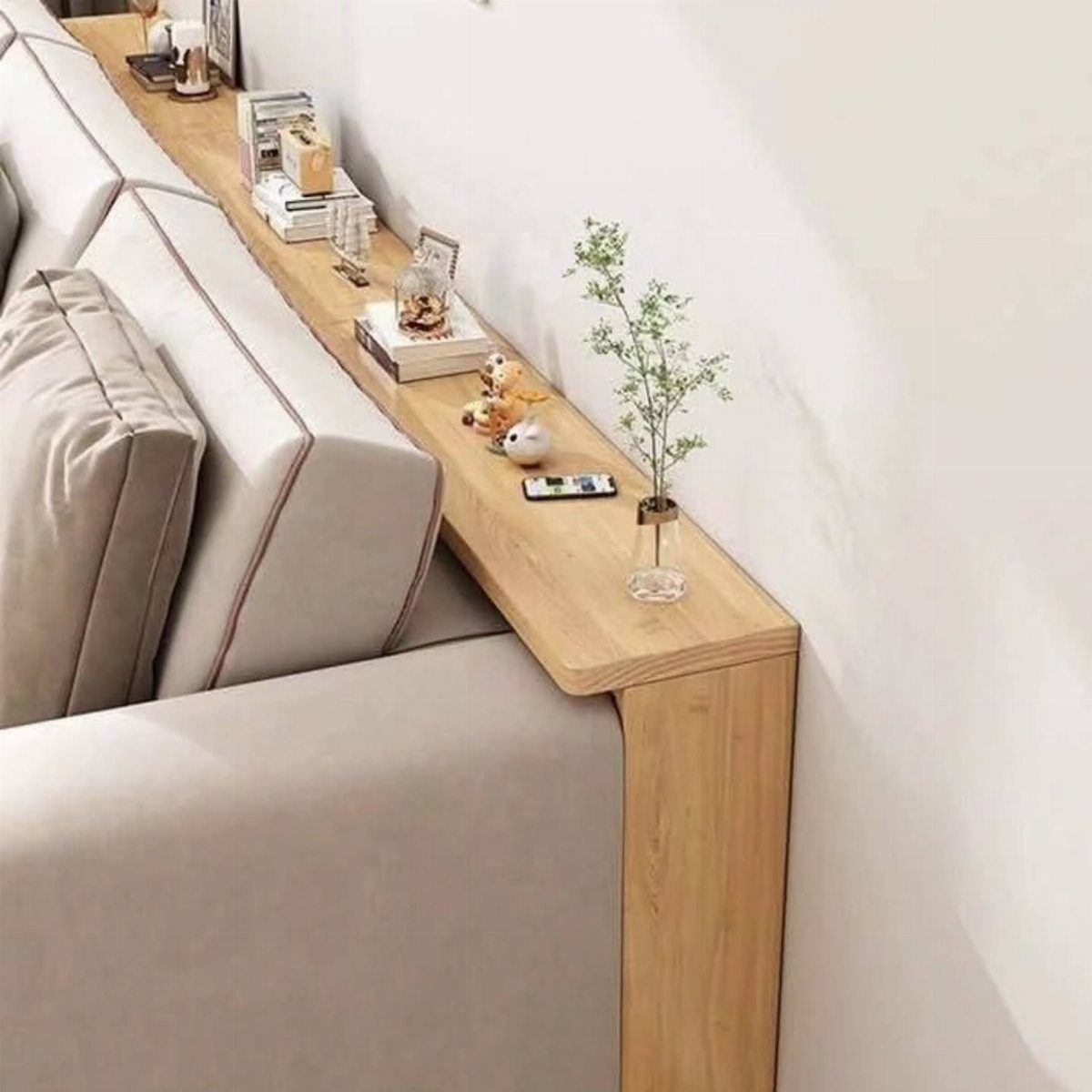 Slim wooden console table behind a beige sofa with a small potted plant.
