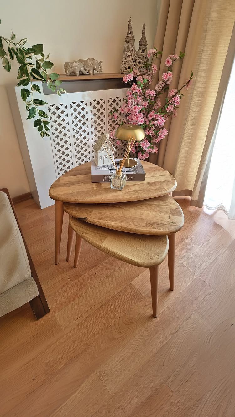 Tiered wooden coffee tables with rounded edges in a bright living room setting.