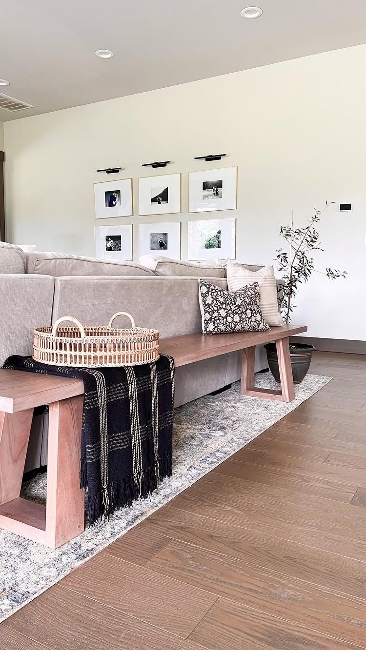 Wooden bench behind a grey sofa with a black throw and woven basket