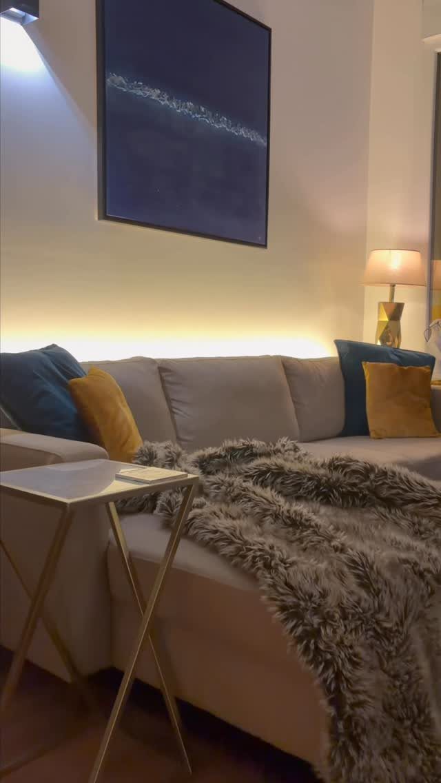 Grey sofa with warm backlight glowing in the space behind it and the wall