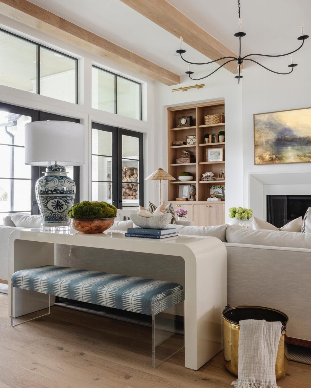 White console table behind a light sofa with a lamp and decorative bowl.
