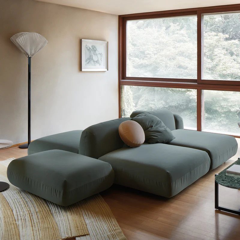Modular olive green sofa positioned away from the wall in a bright living room.