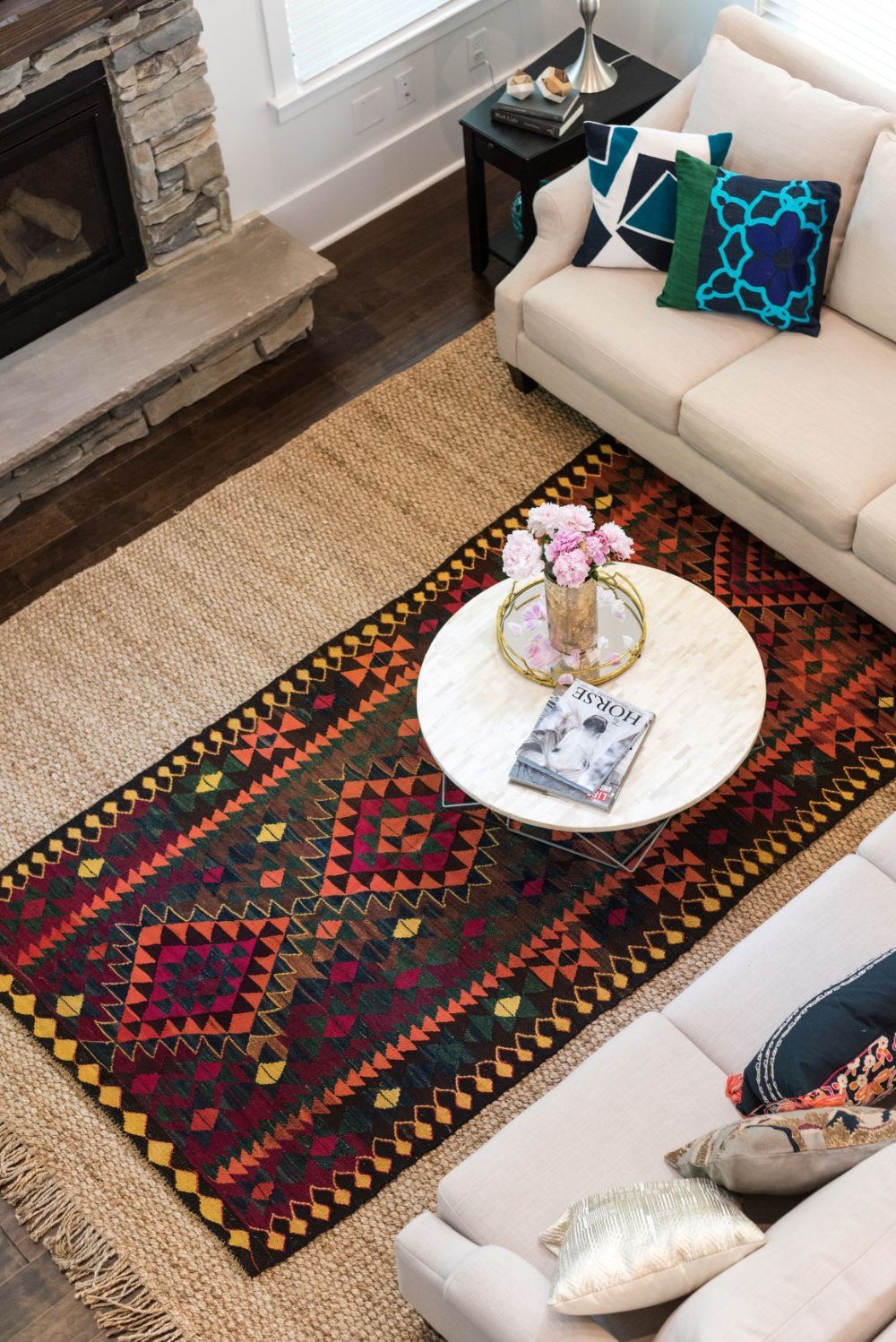 Layered jute and colorful geometric rugs anchoring a living room seating area.