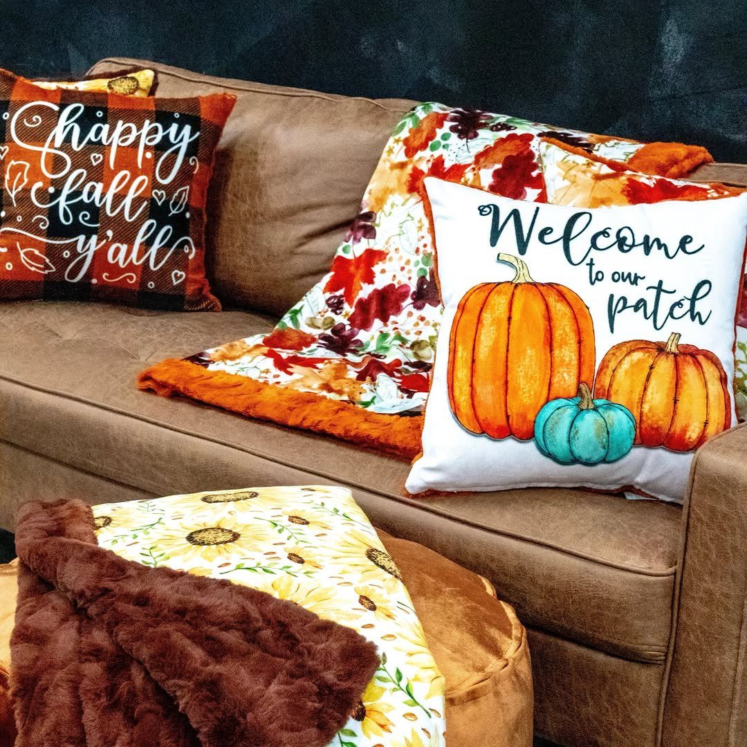 Brown couch with pumpkin and buffalo plaid autumn throw pillows and blankets.