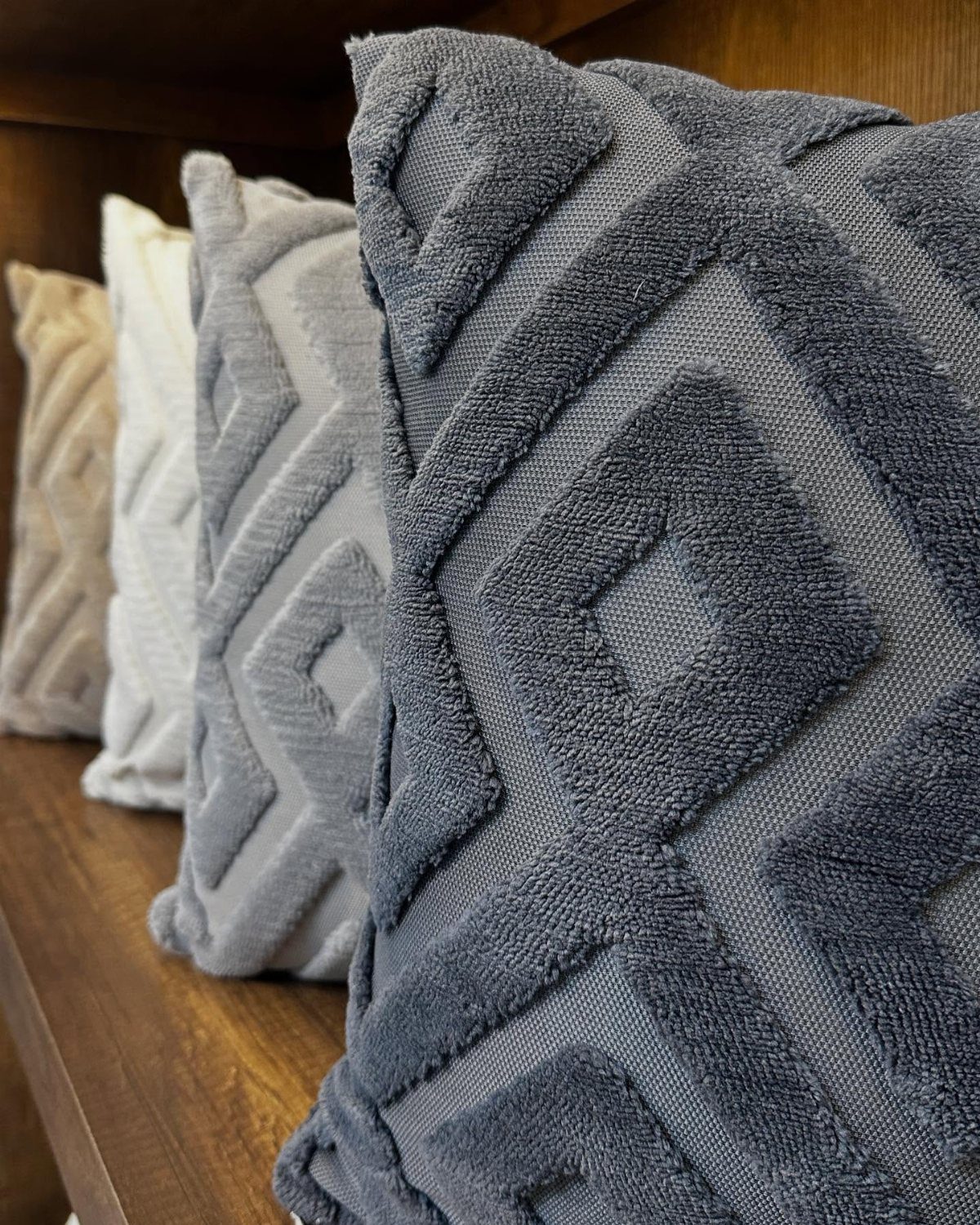 Textured throw pillows with geometric diamond patterns in grey and cream tones.
