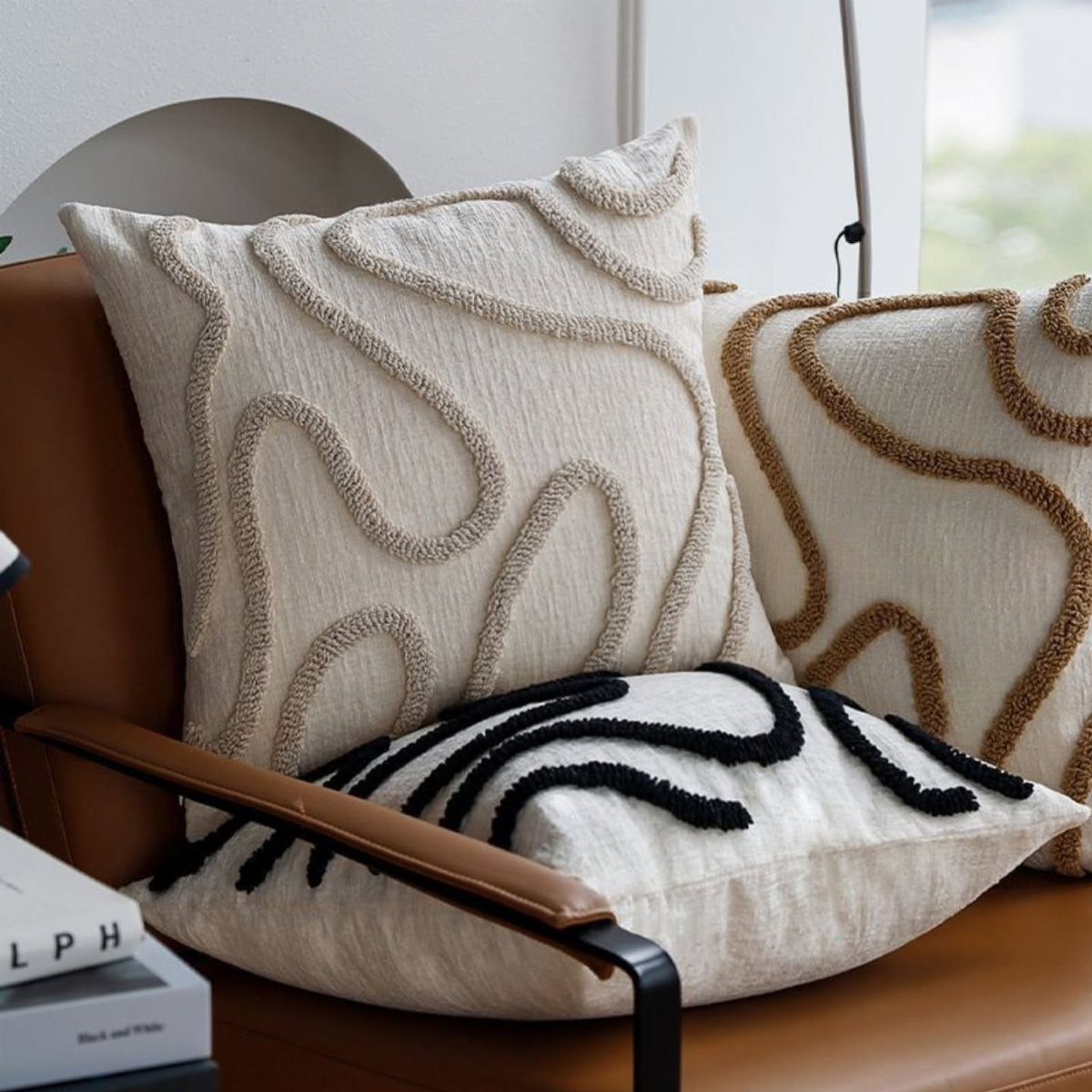 Textured cream throw pillows with swirling patterns on a brown leather couch