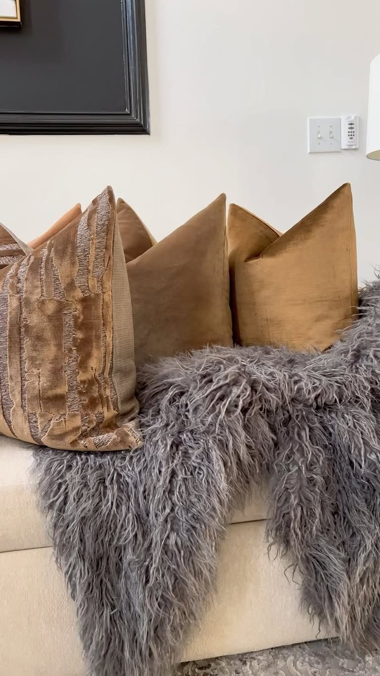 Brown textured throw pillows and a grey faux fur blanket on a sofa.