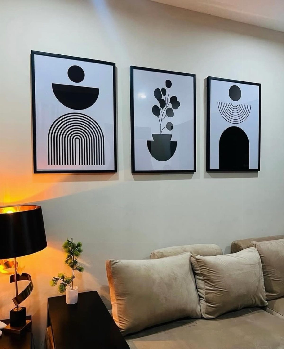 Three black-framed minimalist art prints hanging on a wall above a beige couch.