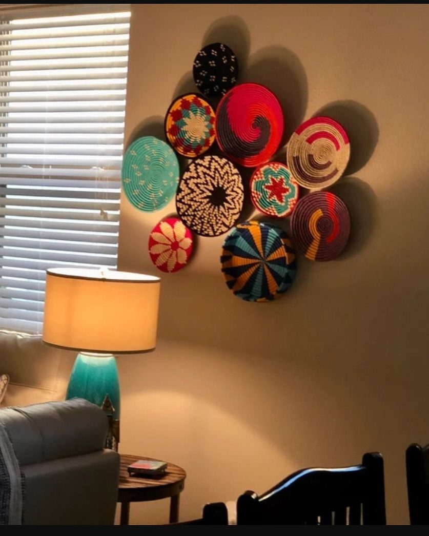 Colorful woven baskets arranged as wall art above a grey couch and lamp.
