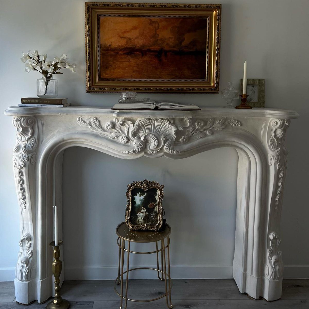 Ornate white antique mantelpiece with a gold-framed painting hanging above it