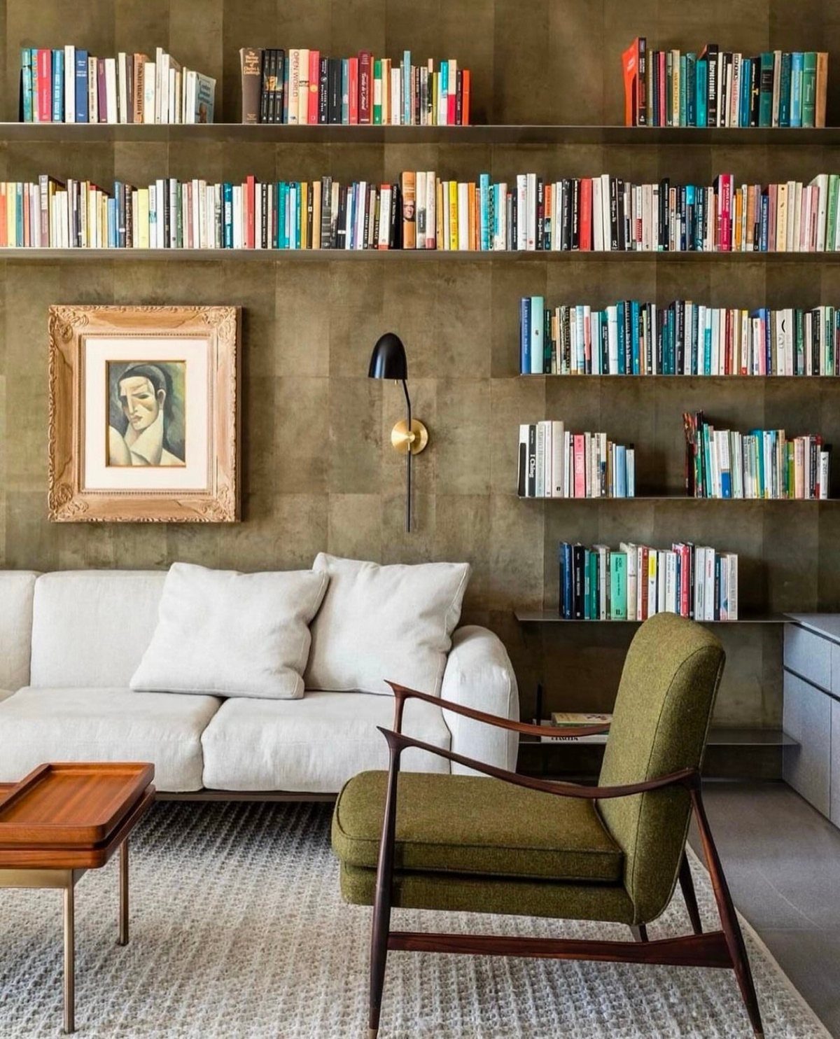 Floating shelves filled with books on a brown textured living room wall.