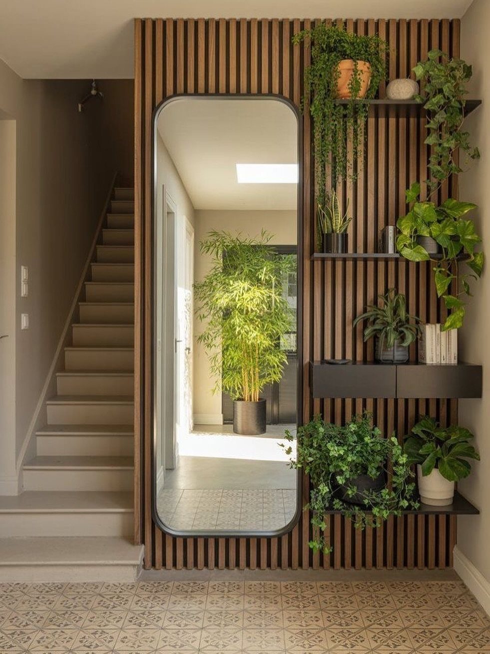 Arched statement mirror against a wooden slat wall with floating plant shelves.