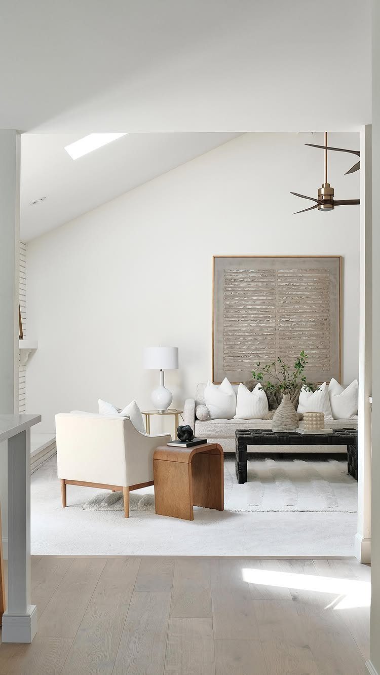 Large textured beige artwork hanging on a white wall above a white sofa.