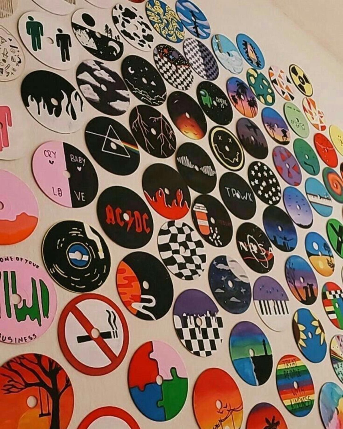 Painted vinyl records with various colorful designs arranged as wall art on white wall